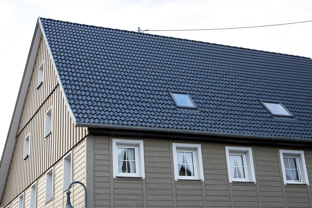 Dachsanierung: Aufbringen einer Nut- und Federschalung auf die alten Dachsparren, Fassade neu gedämmt und mit einer Holzschalung verkleidet (unten Stulpschalung, oben Boden Deckelschalung