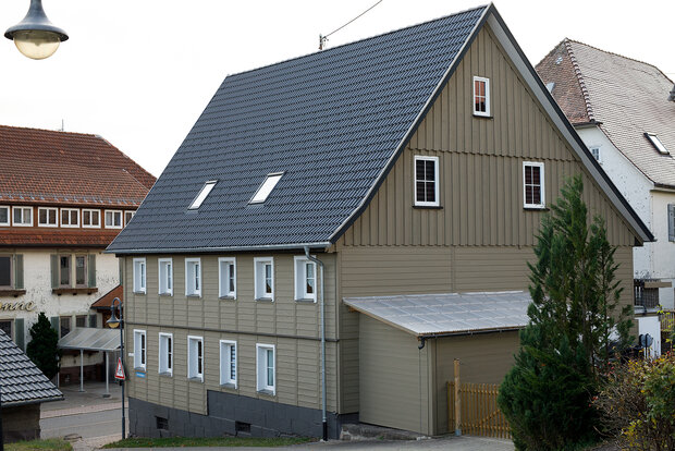 Dachsanierung: Aufbringen einer Nut- und Federschalung auf die alten Dachsparren, Fassade neu gedämmt und mit einer Holzschalung verkleidet (unten Stulpschalung, oben Boden Deckelschalung